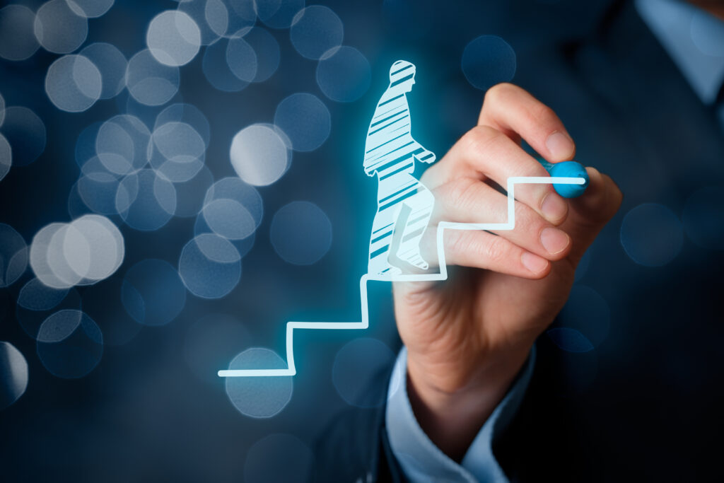 Hand einer Person in Business-Kleidung zeichnet mit einem Stift eine stilisierte Figur, die eine Treppe hinaufsteigt, Symbol für Karriere und Weiterbildung.